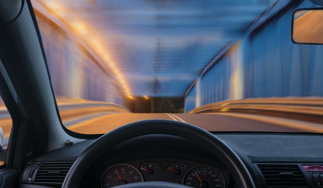 A driver's perspective through the windshield of an automobile as it passes through a tunnel at night.